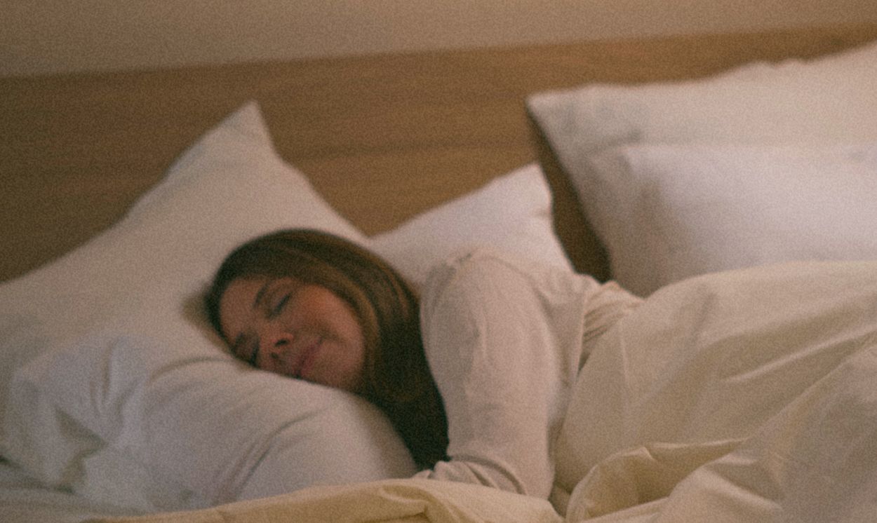 Femme endormie paisiblement dans un lit Kipli avec oreillers et linge de lit en matières naturelles.