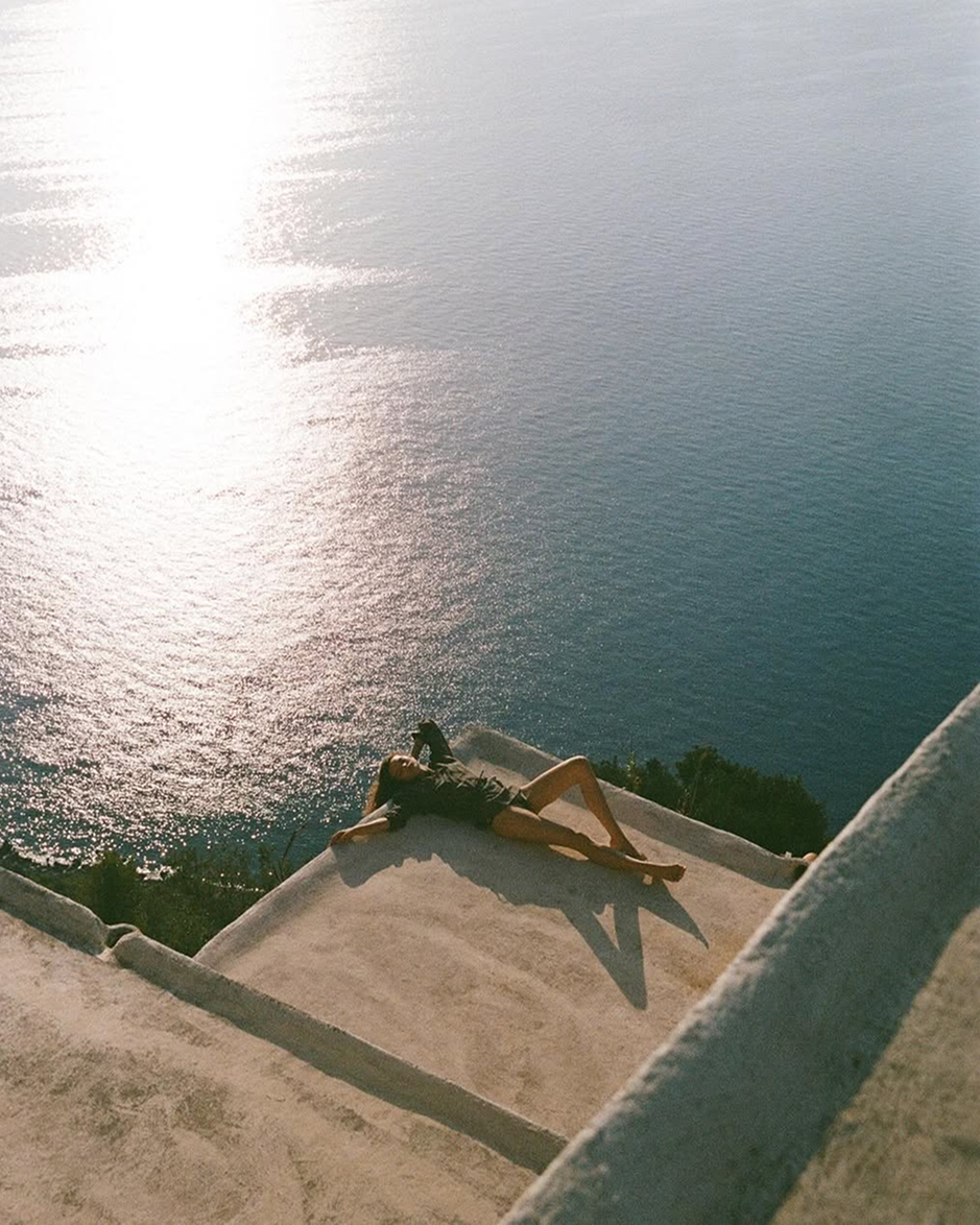 Femme allongée au soleil face à la mer, illustrant un moment de détente et de bien-être en pleine nature, symbole d’un mode de vie apaisé et ressourçant.