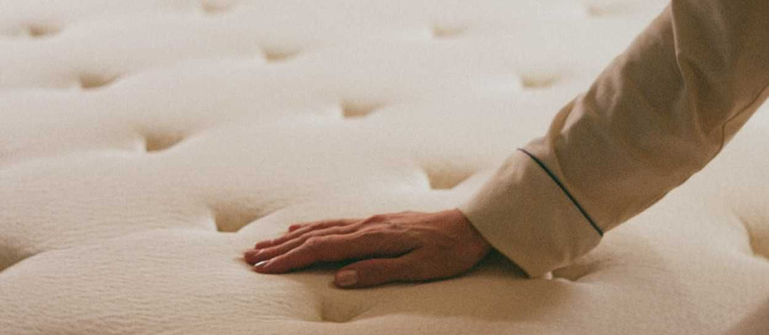 Main posée sur un matelas en latex naturel Kipli pour illustrer son confort et sa durabilité.